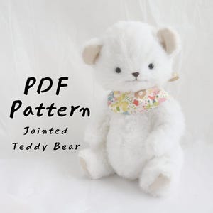 Può includere: Un orsacchiotto bianco snodato con una sciarpa floreale. L'orso ha piccoli occhi scuri e orecchie beige. Il testo "PDF Pattern Jointed Teddy Bear" è visualizzato in nero.