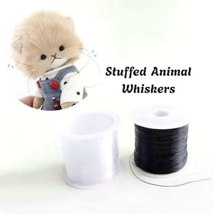 May include: Two spools of thin, flexible filament for Stuffed Animal Whiskers, one clear and one black, shown alongside a small plush cat toy wearing a white shirt and blue overalls with red buttons, demonstrating the application of the whiskers.
