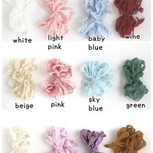 May include: A collection of 12 spools of ribbon in various colors, including white, light pink, baby blue, wine, beige, pink, sky blue, green, creamy white, light purple, purple, and brown.