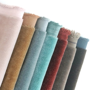 Puede incluir: Una colección de muestras de tela en varios colores, incluyendo rosa, marrón, azul, verde azulado, rojo, gris y negro. La tela parece ser terciopelo.