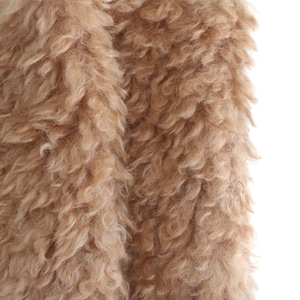 May include: Close-up of a tan, fluffy fabric with a curly texture. The material appears soft and plush, with a dense, shaggy appearance. The fabric is likely used for clothing or home decor.