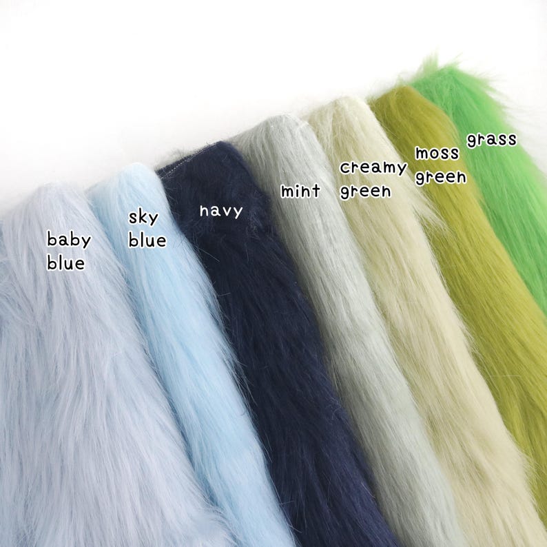 Op de afbeelding: Een collectie kunstbont stofstalen gerangschikt in een rij, met de kleuren gelabeld als baby blue, sky blue, navy, mint, creamy green, moss green en grass. Elke staal toont een lange, zachte en getextureerde pool in de betreffende kleur.
