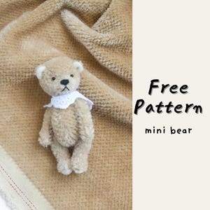 May include: A small, tan teddy bear with a white collar is displayed on a textured, tan fabric. The bear has black eyes and a stitched nose. The text "Free Pattern" and "mini bear" are visible in black font.