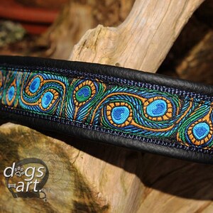 May include: A black leather dog collar with a peacock feather pattern in blue, green, and gold. The collar has a metal D-ring.
