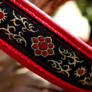 Può includere: Collare per cani in pelle rossa con bordatura nera e dorata. La bordatura presenta un motivo ripetitivo di fiamme stilizzate e disegni floreali.