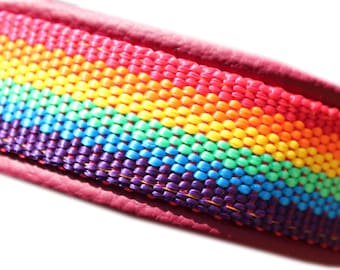 Puede incluir: Primer plano de una correa tejida con los colores del arcoíris y borde burdeos. La correa presenta un espectro vibrante de colores, incluyendo rojo, naranja, amarillo, verde, azul y morado. El diseño tejido apretado crea una textura duradera y visualmente atractiva.