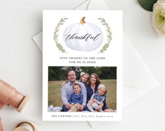Puede incluir: Una tarjeta de Acción de Gracias con una ilustración de acuarela de una calabaza blanca con la palabra "thankful" escrita en ella. La tarjeta también incluye el texto "Give thanks to the Lord for he is good." y una foto de una familia de cinco.