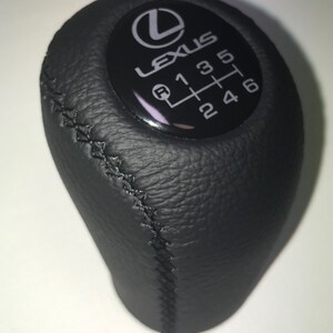 May include: Black leather gear shift knob with a silver Lexus logo and a silver gear pattern with the numbers 1, 2, 3, 4, 5, 6, and R.