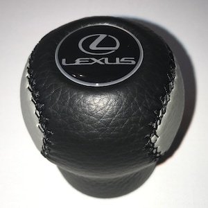 May include: Black leather gear shift knob with a silver and black Lexus logo.