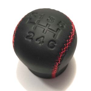 May include: Black leather gear shift knob with red stitching and embossed numbers 1, 2, 3, 4, 5, and 6.