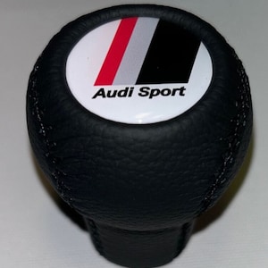 Könnte beinhalten: Schwarzer Leder-Schalthebelknauf mit einem weißen, roten und schwarzen Audi Sport Logo.