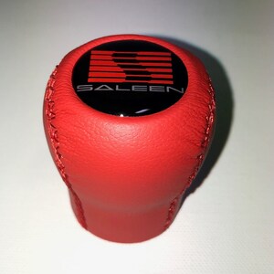 May include: Red leather gear shift knob with a black and red Saleen logo.