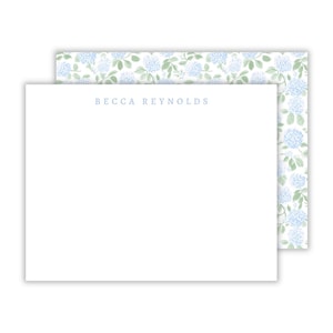 May include: White stationery with the name "BECCA REYNOLDS" in light blue. The top sheet has a floral pattern on the back with blue and green hydrangea flowers. The stationery is perfect for personal notes.