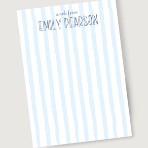 May include: A white notepad with light blue vertical stripes and the text "a note from EMILY PEARSON" at the top.