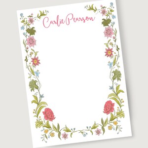 Puede incluir: Papelería blanca con un borde floral. El borde presenta flores rosas, rojas, amarillas y azules con hojas y vides verdes. El nombre "Carlie Pearson" está escrito en rosa en la parte superior.