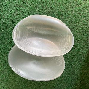 Puede incluir: Una taza de cerámica blanca con asa negra y el texto "But First, Coffee" en negrita negra. La taza se encuentra sobre un fondo borroso, sugiriendo un ambiente acogedor.