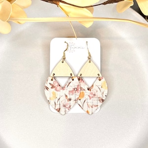 May include: A pair of floral patterned dangle earrings with a wood triangle top and gold hooks. The earrings are on a white card with the word "Tammi" printed on it.