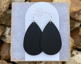 May include: A pair of black leather teardrop earrings with silver hooks. The earrings are on a white card with the text "Designed by Tammi" in pink.