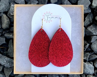 May include: Red glitter teardrop earrings on a white card with the text "Design by Tammi's".