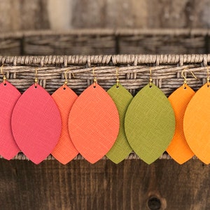 May include: Five pairs of leather earrings in the shape of leaves. The earrings are in shades of red, orange, and green.