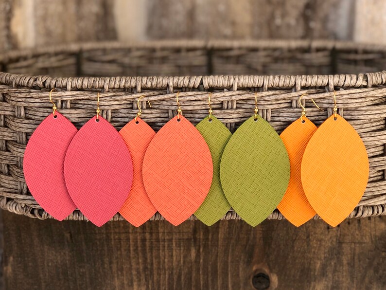 May include: Five pairs of leather earrings in the shape of leaves. The earrings are in shades of red, orange, and green.