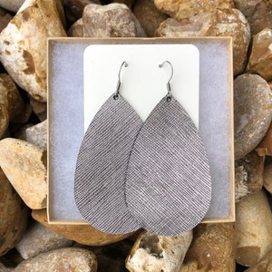 May include: A pair of silver teardrop-shaped leather earrings with silver hooks.