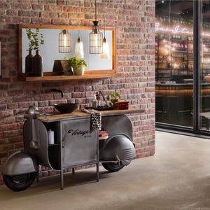 Könnte beinhalten: Einzigartiger Badezimmerwaschtisch im Vintage-Roller-Design. Der graue Metallschrank hat eine Holzplatte, ein schwarzes Waschbecken und einen Spiegel mit dekorativer Beleuchtung. Die Backsteinmauer trägt ein "Carpe Diem"-Schild.