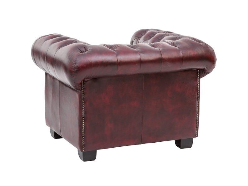Puede incluir: Un sill&oacute;n de cuero burdeos con respaldo capiton&eacute; y detalles de botones. El sill&oacute;n tiene forma cuadrada y patas de madera.