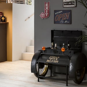 Könnte beinhalten: Ein schwarzer Metall-Barwagen, der als Oldtimer-Fahrzeug gestaltet ist, mit goldfarbenen Rädern und dem Text "Indian Quick Delivery". Der Wagen fasst mehrere Flaschen und hat zwei orangefarbene Lichter.