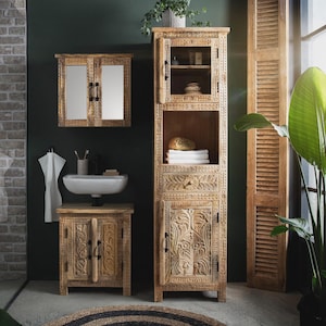 Könnte beinhalten: Ein Badezimmer-Set mit geschnitzten Holzmöbeln. Das Set umfasst einen hohen Schrank mit Glastüren, einen Wandschrank mit Spiegeln und einen Waschtisch mit Waschbecken. Das Holz hat eine natürliche Oberfläche, und der Raum hat eine dunkelgrüne Wand.
