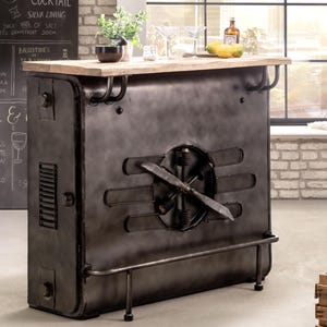Könnte beinhalten: Eine Bar im industriellen Stil mit einem verwitterten Metallfinish und einer hellen Holzplatte. Die Bar hat ein propellerartiges Design auf der Vorderseite und eine Fußstütze. Eine Tafel zeigt Cocktails und Biere.
