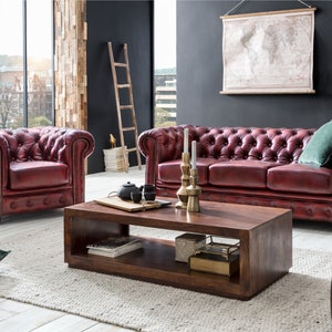 Puede incluir: Un sal&oacute;n con un sof&aacute; y un sill&oacute;n de cuero rojo, una mesa de centro de madera y un mapa del mundo colgado en la pared. La habitaci&oacute;n tiene un ambiente r&uacute;stico e industrial.