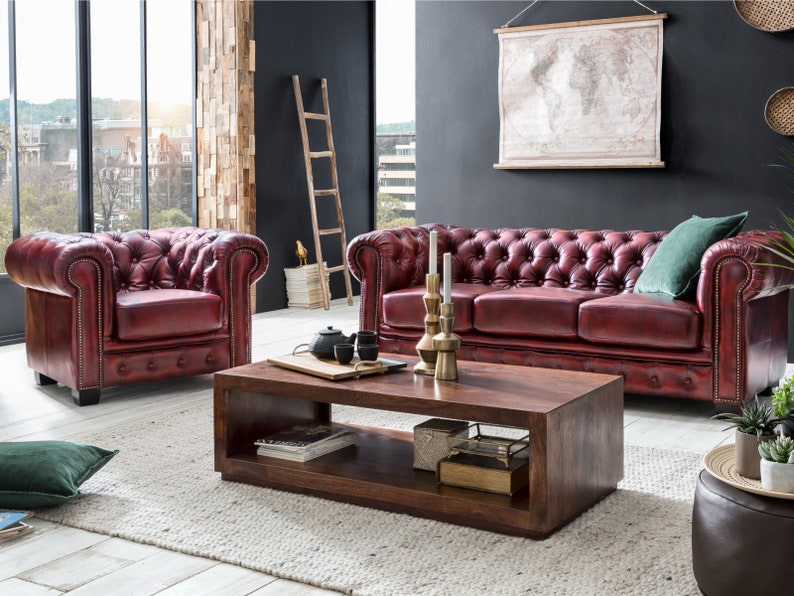 Puede incluir: Un sal&oacute;n con un sof&aacute; y un sill&oacute;n de cuero rojo, una mesa de centro de madera y un mapa del mundo colgado en la pared. La habitaci&oacute;n tiene un ambiente r&uacute;stico e industrial.