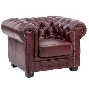 Puede incluir: Un sill&oacute;n de cuero rojo oscuro con capiton&eacute; y respaldo enrollado. El sill&oacute;n tiene un dise&ntilde;o cl&aacute;sico con estructura y patas de madera.