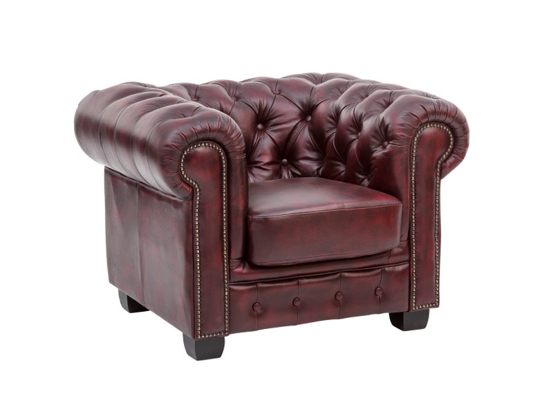 Puede incluir: Un sill&oacute;n de cuero rojo oscuro con capiton&eacute; y respaldo enrollado. El sill&oacute;n tiene un dise&ntilde;o cl&aacute;sico con estructura y patas de madera.
