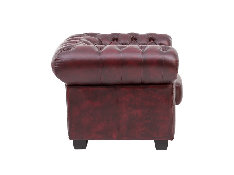 Puede incluir: Un sill&oacute;n de cuero burdeos con respaldo capiton&eacute; y brazos enrollados. El sill&oacute;n tiene un dise&ntilde;o cl&aacute;sico y est&aacute; tapizado en un cuero rico y desgastado.