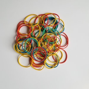 Puede incluir: Un montón de gomas elásticas de colores en rojo, amarillo, azul y verde.