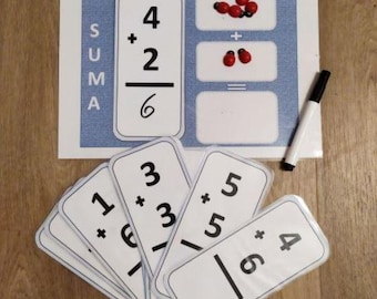 May include: A set of white cards with black numbers and plus signs for learning addition. The cards have a line for the answer. The cards are arranged in a fan shape. The top card shows the equation 4 + 2 = 6. The word "SUMA" is written vertically on the card.