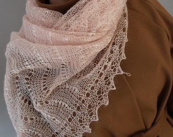 May include: A pale pink, open-weave knitted shawl with a decorative, scalloped edge. The shawl is draped over a brown coat. The intricate design of the shawl creates a soft, textured appearance, adding visual interest to the garment.