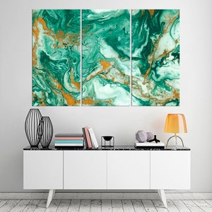May include: A three-piece abstract art print set featuring a swirling green and gold marble pattern. The print is displayed on a white wall above a white cabinet with black legs.