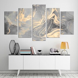 May include: A five-piece abstract canvas wall art set featuring a gray and gold marble design. The artwork is displayed on a white wall above a white dresser with black legs.