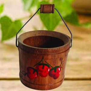 May include: A small, wooden bucket with a dark brown finish. The bucket features a metal handle with a wooden grip and is decorated with three red strawberries. The strawberries have green leaves and are painted on the front of the bucket.