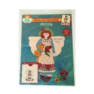 May include: Plaid iron-on transfer featuring a design of an angel holding a cat and flowers, with the text "Heavenly Friends" and "Purrfect Pals." Includes instructions for use on dark or light fabric. The package also shows a sample of the finished design.