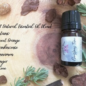 May include: A small amber glass bottle of "Christmas Time" essential oil blend with a black cap. The label reads "purple bag" and lists the blend's ingredients: Sweet Orange, Frankincense, Cinnamon, Ginger, and Clove. The bottle is surrounded by natural elements.