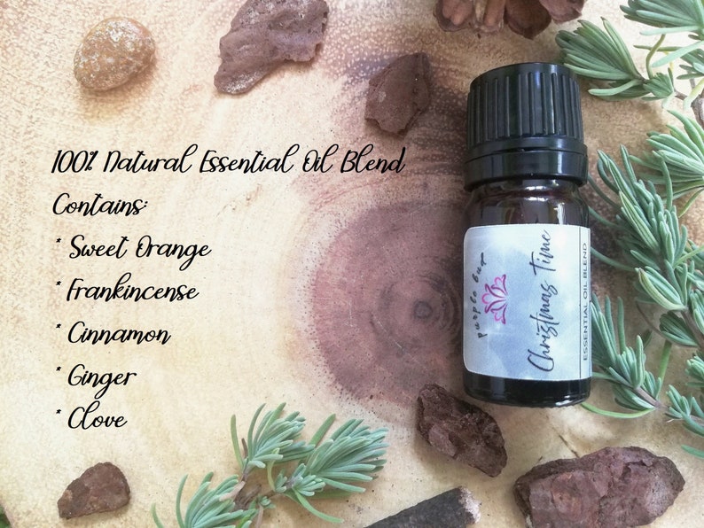 May include: A small amber glass bottle of "Christmas Time" essential oil blend with a black cap. The label reads "purple bag" and lists the blend's ingredients: Sweet Orange, Frankincense, Cinnamon, Ginger, and Clove. The bottle is surrounded by natural elements.