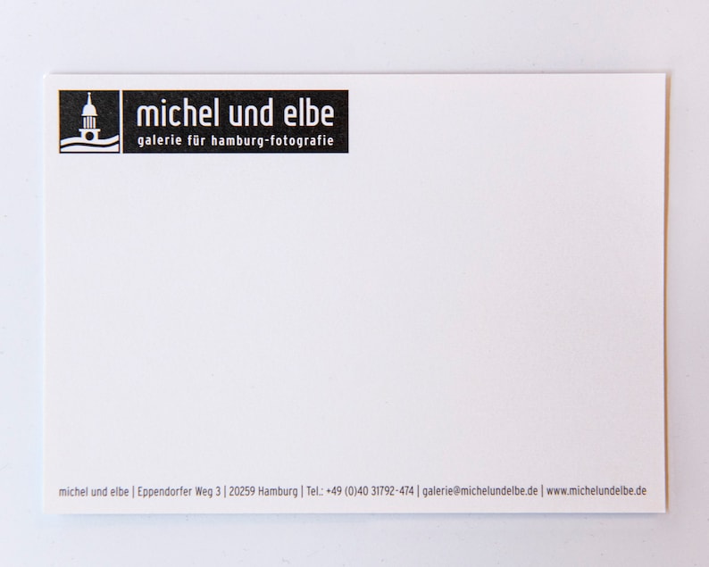 May include: Black and white business card with the text "michel und elbe" and "galerie f&uuml;r hamburg-fotografie". The card also includes contact information for the business.