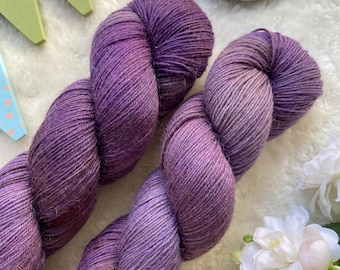 Può includere: Due gomitoli di filato viola con un gradiente di colore. Il filato è avvolto a forma di palla ed è pronto per essere utilizzato per la maglia o l'uncinetto.