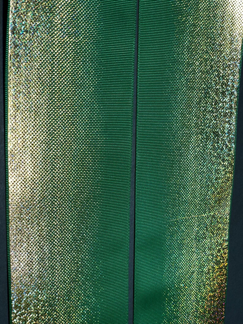 May include: Two green ribbons with a shimmery gold finish. The ribbon on the left has a subtle iridescent sheen.