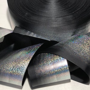 May include: Black iridescent ribbon with a subtle sparkle. The ribbon is rolled up and folded in a decorative way.