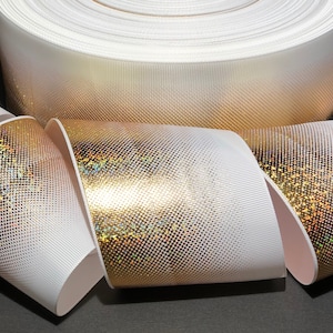 May include: White and gold iridescent ribbon with a subtle shimmer. The ribbon is rolled up and has a gradient effect from white to gold.